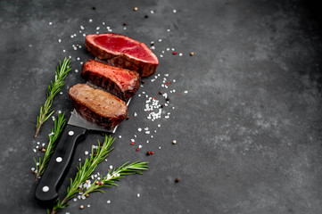 Three pieces of meat grilled over a meat knife. Three types of frying meat, rare, medium, well done with spices   on stone background with  copy space for your text