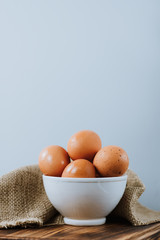 Сhicken eggs in a white bowl on a wooden board.