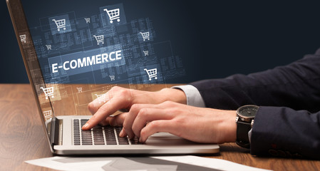 Naklejka na ściany i meble Businessman working on laptop with E-COMMERCE inscription, online shopping concept