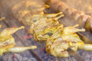 Quail on the grill. Several quails are strung on a skewer and fried on coals.