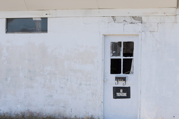 An abandoned building with a no trespassing sign on the door.