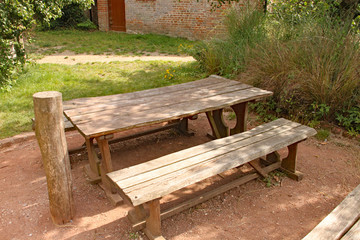 A rustic picnic table and bench in a playground