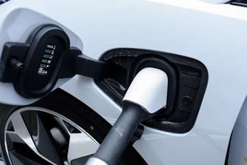 Close up of a white power supply plugged into an electric car being charged