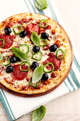 Pizza with salami, jalapeno pepper, black olives and mozzarella cheese. Bright background