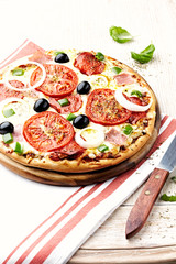 Pizza with tomatoes, ham, green pepper, onion and black olives. 