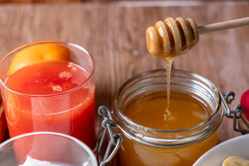 jar of honey and dipper on wooden background
