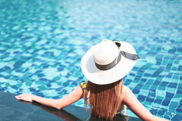 Summer and vacation concept. Young woman in sun hat relaxing in swimming pool.