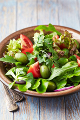 Salad with green Olives, Tomatoes and Cucumber on wooden Background. Healthy Snack Idea.