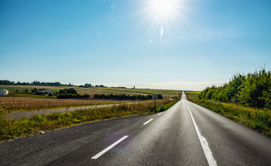 Fototapeta premium Empty long mountain road to the horizon on a sunny summer day at bright sunset