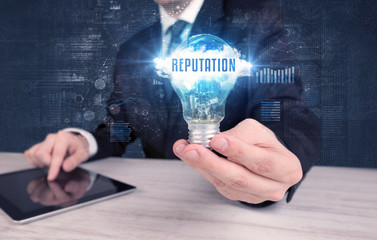 Businessman holding a light bulb with REPUTATION inscription, new business concept