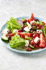Healthy and tasty salad with feta cheese, various tomatoes, olives, cucumber, onion and lettuce.