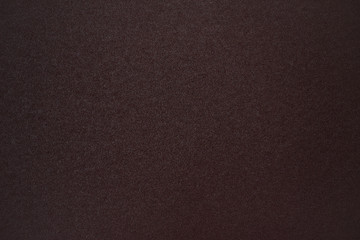 Dark maroon coarse grained sandpaper, background.