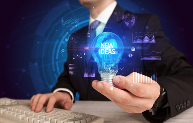 Obraz premium Businessman holding lightbulb with NEW IDEAS inscription, Business idea concept