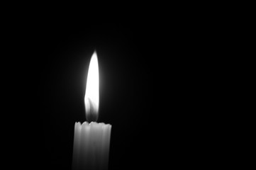 Monochrome one glowing candle on black background 