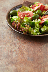 Salad with green Olives, Tomatoes and Cucumber on rustic Background. Healthy Snack Idea. Copy space. 