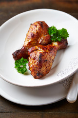 Spicy Chicken Drumsticks with fresh herbs. Brown wooden background.