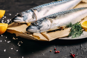 Mackerel with spices and herbs on a plate, fish still life on a dark background, assorted peppers,...