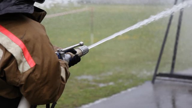 Close-up of firefighter extinguishing fire with fire hose
