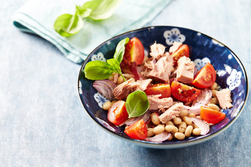Healthy salad with tuna, cannellini bean and tomatoes. Bright wwooden background
