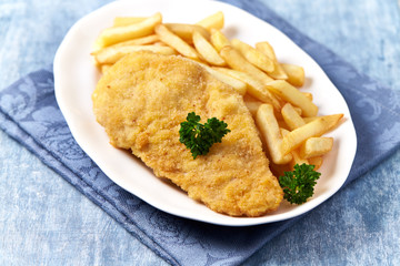 Pork Schnitzel with french fries on wooden background.
