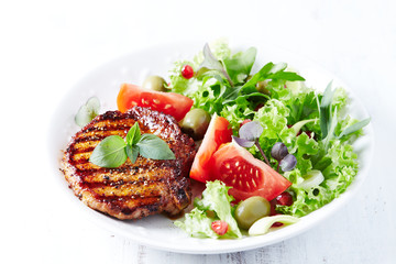 Grilled pork steak with fresh salad. White background