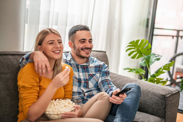 Happy couple preparing to watch a movie at home