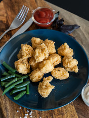 food, slices of fried chicken breaded with green beans, a sprig of basil and sauces, serving example