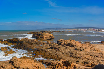 Rocky beach with foamy waves of blue Atlantic ocean shot in Essaouira.