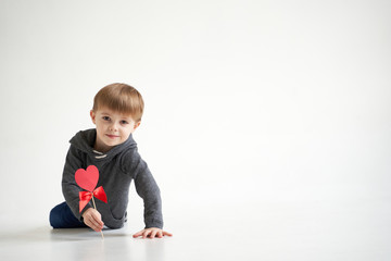 Naklejka premium Sweet boy holding red paper heart on white background. Valentines day or kids healthcare, medical concept