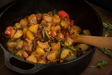 Vegan mixed stewed vegetables with spices and herbs in cast iron pot