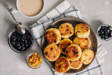 Curd pancake with tea and jam for breakfast. Plate of cottage cheese with raisins on a light background. Healthy Food, Quick Breakfast Recipe