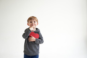 Sweet boy holding red paper heart on white background. Valentines day or kids healthcare, medical concept