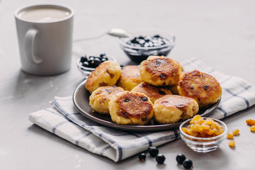 Curd pancake with tea and jam for breakfast. Plate of cottage cheese with raisins on a light background. Healthy Food, Quick Breakfast Recipe