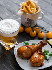 food, fried chicken drumsticks with french fries, cherry tomatoes, sauces, a beer on a plate, on a black background, serving example