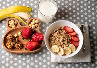 banana, strawberries, nuts, granola, cheese and a glass of milk - a healthy breakfast