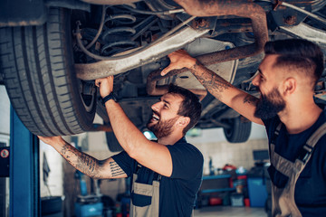 Young mechanics change car wheel in auto repair shop