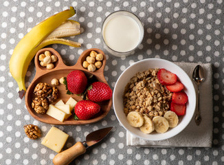 banana, strawberries, nuts, granola, cheese and a glass of milk - a healthy breakfast