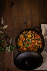 Vegan mixed stewed vegetables with spices and herbs in cast iron pot