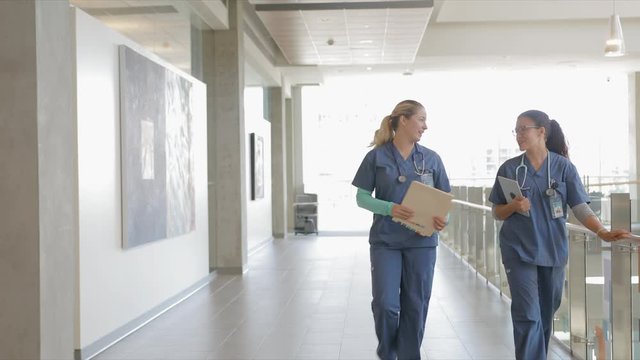 Female Nurses Walking And Talking In Hospital Corridor