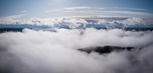 Fototapeta premium Aerial view of morning fog hovering over sunny lake