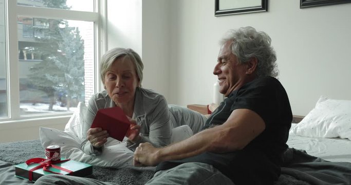 Senior Couple Opening Valentine's Day Card In Bed