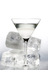Glass with martini and several pieces of melting ice isolated on a neutral background