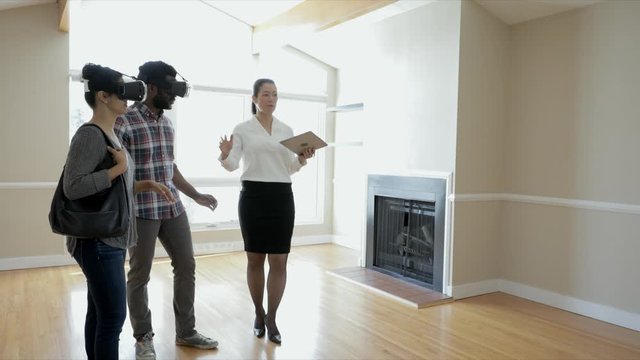 Realtor showing new house to couple wearing virtual reality simulator glasses