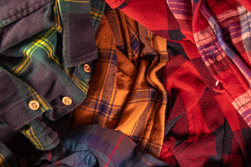 brightly colored checkered vintage flannel shirts lie together in a heap green yellow red blue...