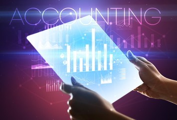 Hand holding futuristic tablet with ACCOUNTING inscription above, modern business concept
