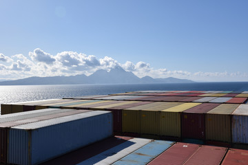 Containers loaded on the cargo ship sailing near sea coast.