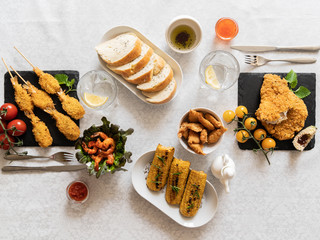 food, breaded shrimp with cherry tomatoes, french fries, lettuce, herbs, bread, drinks, salad on a black background, serving example