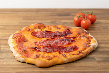 homemade pizza margherita with tomato sauce, mozzarella, served on a floured wooden table decorated with fresh tomatoes