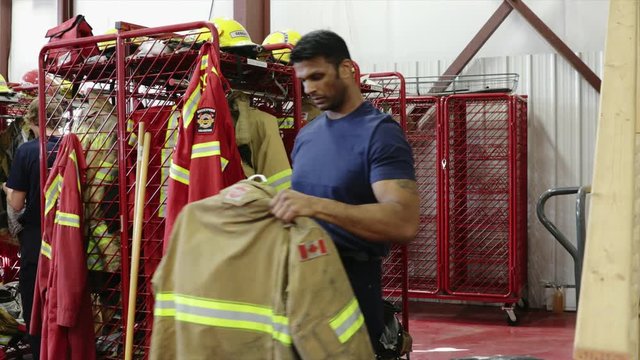 Male firefighter retrieving uniform from rack in fire station