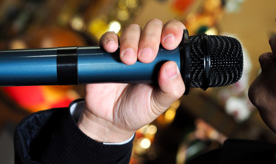 Male singer holding a wireless microphone during public performance